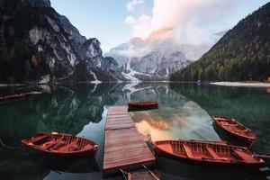 casi listo para nadar. Barcos de madera en el muelle del lago de cristal con majestuosa montaña detrás. reflejo en el agua