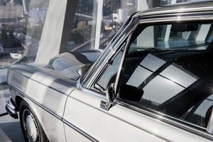 Hood and windows. An old white car captures from behind that parked indoor photo