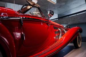 Plane hanging on background. Detailed focused photo of the awesome historical red car with a headlight and side mirror