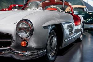 Car show. Two vehicles in the background. Headlights of retro autobobile in a front of focused camera. Indoor black tile photo