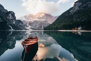 concepción de viajar. barco de madera en el lago de cristal con majestuosa montaña detrás. reflejo en el agua. la capilla está en la costa derecha foto