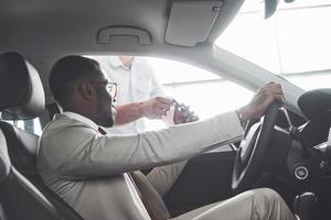 Young black businessman test drive new car. Rich african american man