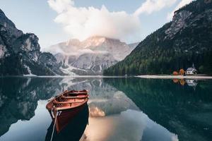 buen día tranquilo. barco de madera en el lago de cristal con majestuosa montaña detrás. reflejo en el agua. la capilla está en la costa derecha foto