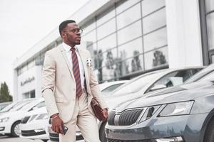 visitando concesionario de automóviles. hombre de negocios negro casual en un traje cerca del coche foto