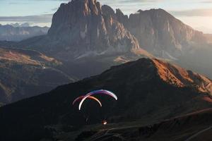 The Seceda dolomites and two paragliders on the sunset lights