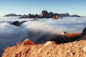 Photo from the edge of the hill and with beautiful mountains with lots of clouds and building on the right