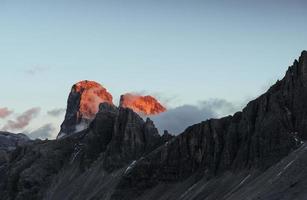 Sun on two peaks and fog on the rocks. Tre Cime mountains captured at sunset time photo