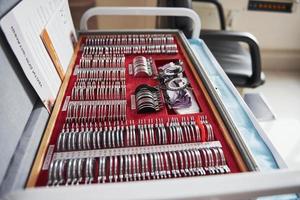 Red box lying on the table with ophthalmic device and many of the lenses photo