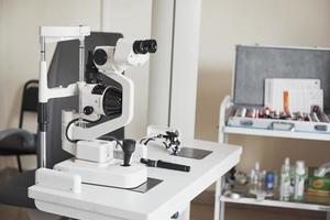 Clear and white room. Photo of medical apparatus standing in the office with other equipment at background