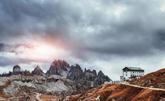 Sun which breaks through the clouds creates a colorful sight. Building standing high on the mountains near the bunch of cliffs with mist photo