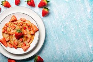 Pancakes with fresh strawberry on a blue wooden background photo