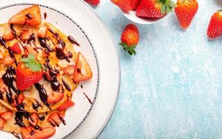 Pancakes with fresh strawberry on a blue wooden background photo