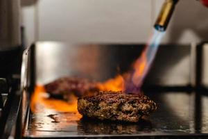 Some patties of ground meat with a flame with the blowtorch photo