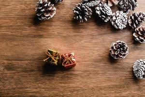 conos de pino sobre fondo de madera. decoración navideña con dos mini regalos. foto