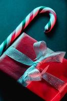 piruleta de navidad y regalo rojo sobre fondo oscuro foto