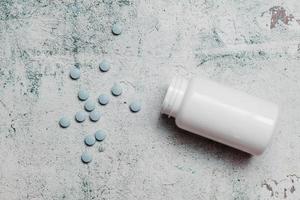 blue pills and canister on concrete background photo