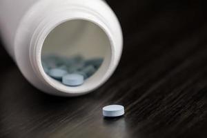 Medication pill in a row against a wood background. White pill bottle photo