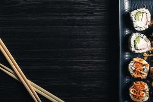 Sushi rolls with chopsticks and soy sauce on dark background. Space text photo