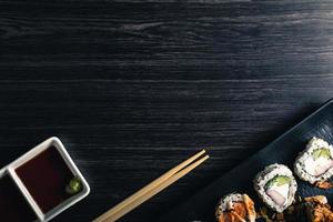 Sushi rolls with chopsticks and soy sauce on dark background. Space text photo
