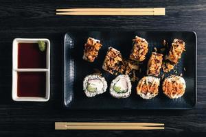 Sushi rolls with chopsticks and soy sauce on dark table. Top view photo