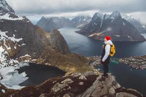 Man traveler hiking on Reinebringen mountain ridge in Norway lifestyle adventure traveling