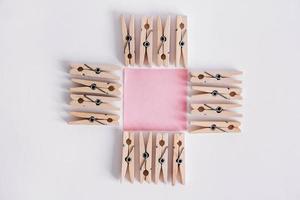 Pinzas para la ropa de madera y pegatinas de color rosa sobre un fondo blanco. foto