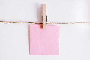 Pink stickers on clothesline with wooden clothespin on white background
