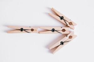 Wooden clothespins on white background with folded arrow. View from above photo