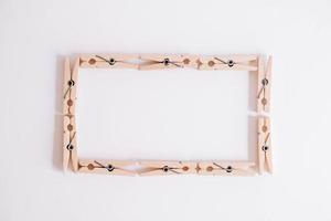 Wooden clothespins on a white background which are folded into a rectangle. View from above. Place for your text photo