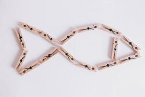 Wooden clothespins on a white background which are composed in the form of a fish icon photo