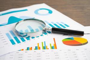 Magnifying glass on charts graphs paper. Financial development, Banking Account, Statistics, Investment Analytic research data economy, Stock exchange trading, Business office company meeting concept. photo