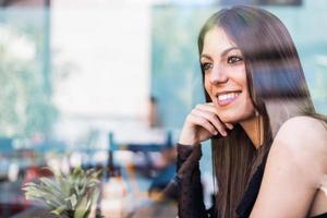 Happy young woman seating in a restaurant photo