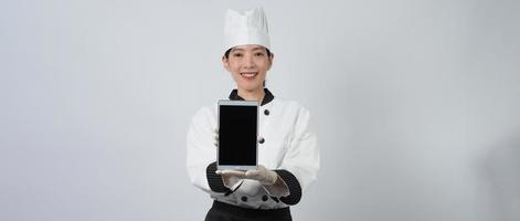 Chef mujer asiática sosteniendo un teléfono inteligente o tableta digital y recibió un pedido en línea foto