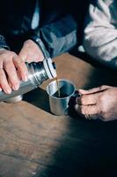 Senior couple hands pouring coffee from thermos photo