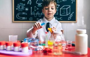 Serious little boy playing with chemical liquids photo