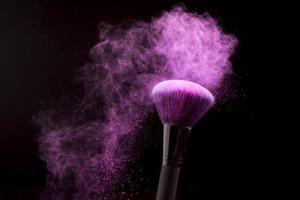 makeup brush with purple powder dust dark background