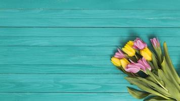 top view yellow pink tulip flowers green wooden desk photo