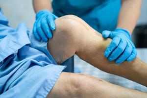 Physiotherapist doing physical therapy with patient at knee joint replacement in nursing hospital ward, healthy strong medical concept photo