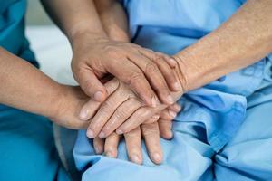 Tomados de la mano anciana asiática o anciana paciente con amor, cuidado, ánimo y empatía en la sala del hospital de enfermería, concepto médico fuerte y saludable foto