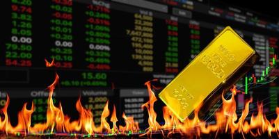 Gold bullion at fire flame and trading chart table background photo