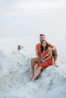 young couple in orange clothes with dog photo