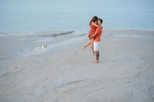 young couple in orange clothes with dog photo