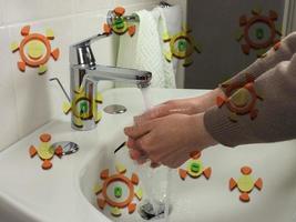 Hombre irreconocible lavándose las manos con virus superpuestos foto