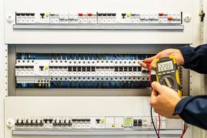 A male electrician works in a switchboard photo