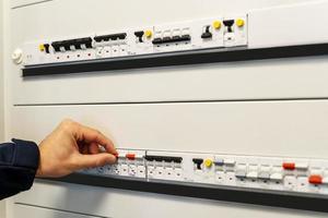 Close up of the hand of a male electrician works in a switchboard photo