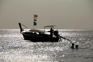 Silhouette of a couple and boat with flags on a bright background of the sea landscape. photo