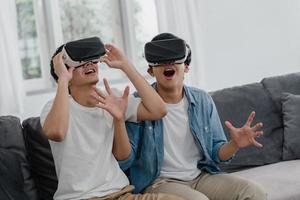 Young Asian Gay couple using technology funny at home, Asia lover guy lgbtq feeling happy fun and virtual reality, VR playing games together while lying sofa in living room at home concept. photo