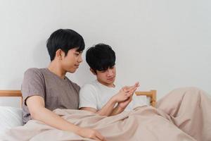 Guapo pareja gay asiática hablando en la cama en su casa. joven asiático lgbtq feliz relajarse descansar juntos pasar tiempo romántico después de despertarse en el dormitorio de la casa moderna en el concepto de la mañana. foto