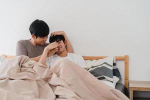 Handsome Asian gay couple talking on bed at home. Young Asian LGBTQ guy happy relax rest together spend romantic time after wake up in bedroom at modern house in the morning concept. photo