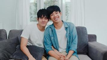 Portrait Young Asian Gay couple feeling happy smiling at home. Asian LGBTQ men relax toothy smile looking to camera while lying on sofa in living room at home in the morning concept. photo